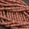 Close-up of pink and beige beads stacked on a dark surface