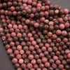 Close-up of faceted rhodonite beads on a dark background