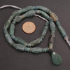 Ancient bead necklace with a coin for scale on a dark background