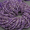 Close-up of a string of purple beads on a gray surface