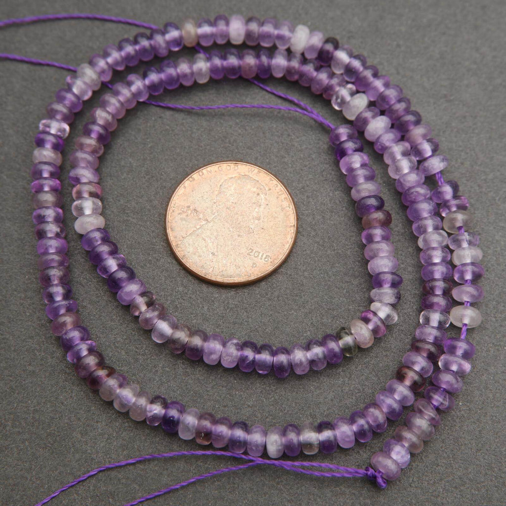 Purple beaded necklace with a coin for scale on a gray background