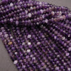 Close-up of a strand of purple beads on a gray surface