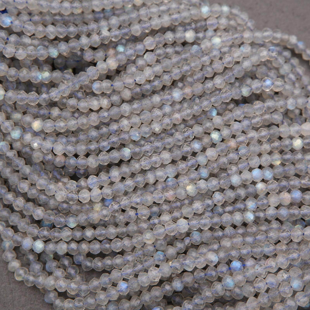 Close-up view of densely arranged faceted labradorite beads with strong blue, green, and gold iridescent reflections.