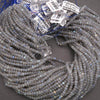 Bundled strands of faceted labradorite beads, shimmering with pale gray tones and light blue flashes.