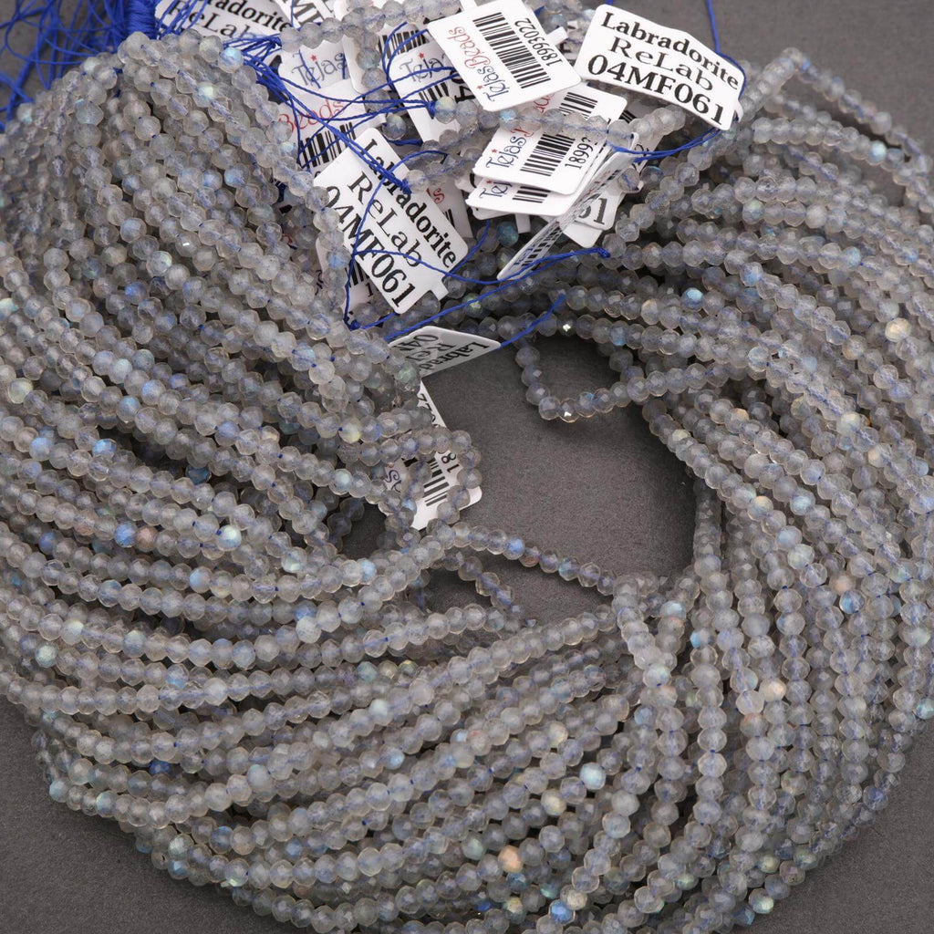 Bundled strands of faceted labradorite beads, shimmering with pale gray tones and light blue flashes.
