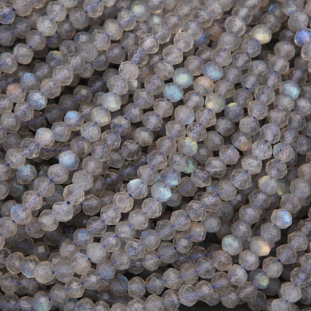 Close-up of faceted round labradorite beads with gray body color and flashes of blue and gold iridescence.