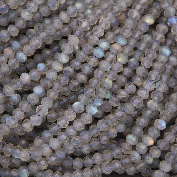 Close-up of faceted round labradorite beads with gray body color and flashes of blue and gold iridescence.