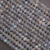Strands of small faceted labradorite beads showing subtle gray tones with scattered blue and golden labradorescence.