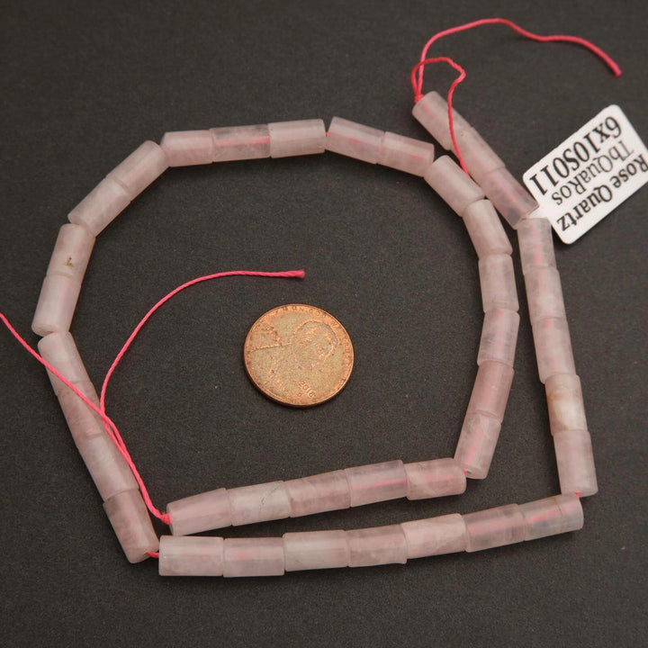 String of cylindrical beads with a penny for scale on a dark surface