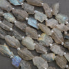 Close-up of raw labradorite beads on a dark surface