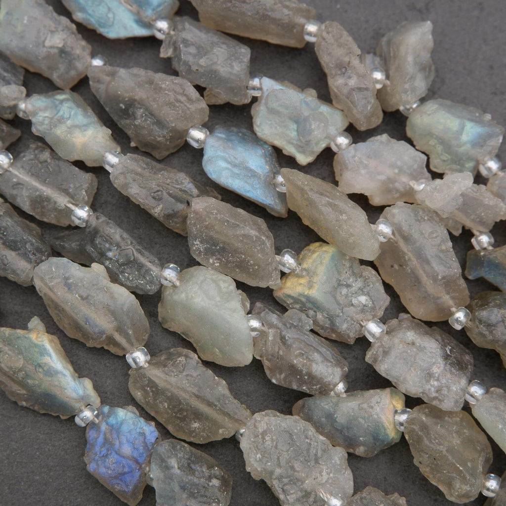 Close-up of raw labradorite beads on a dark surface