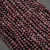 Close-up of a strand of faceted purple beads on a dark background