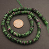 Green and purple bead necklace with a penny for scale on a gray background