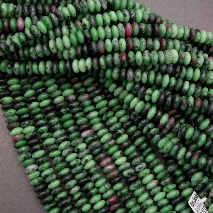 Ruby zoisite rondelle bead strands with product tags visible, showing natural gemstone color mix and uniform bead sizing.