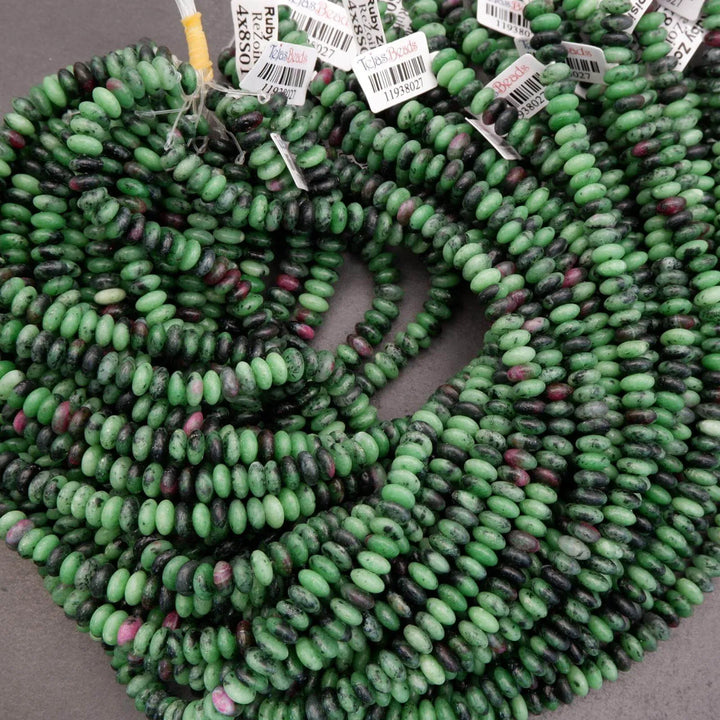 Bundle of ruby zoisite rondelle bead strands arranged in overlapping rows, showing green tones with black and pink accents.