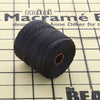 Angled view of black S-Lon TEX 210 nylon bead cord wound around a spool on a gridded macrame work surface.