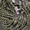 Green beads with price tags on a gray surface