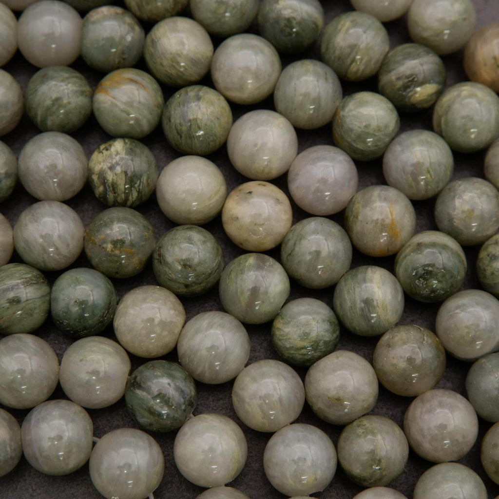 Close-up of green and beige marbled beads on a dark background