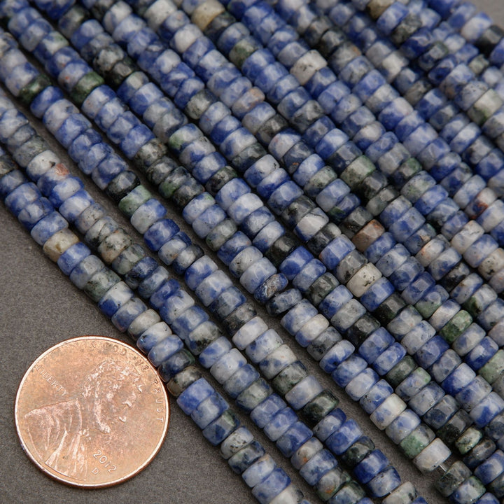 Polished sodalite heishi beads in blue and white tones displayed beside a penny for scale.