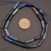 String of blue and black beads with a coin for scale on a gray surface