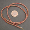 Beaded string with a penny for scale on a gray background