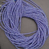 Coiled string of small purple beads on a gray background