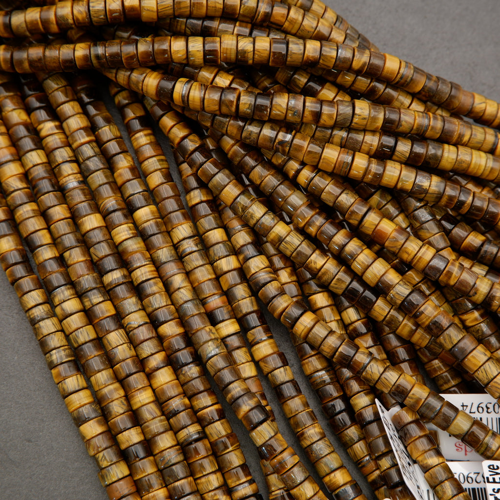 Assorted tiger’s eye heishi bead strands arranged in overlapping rows on a neutral background.