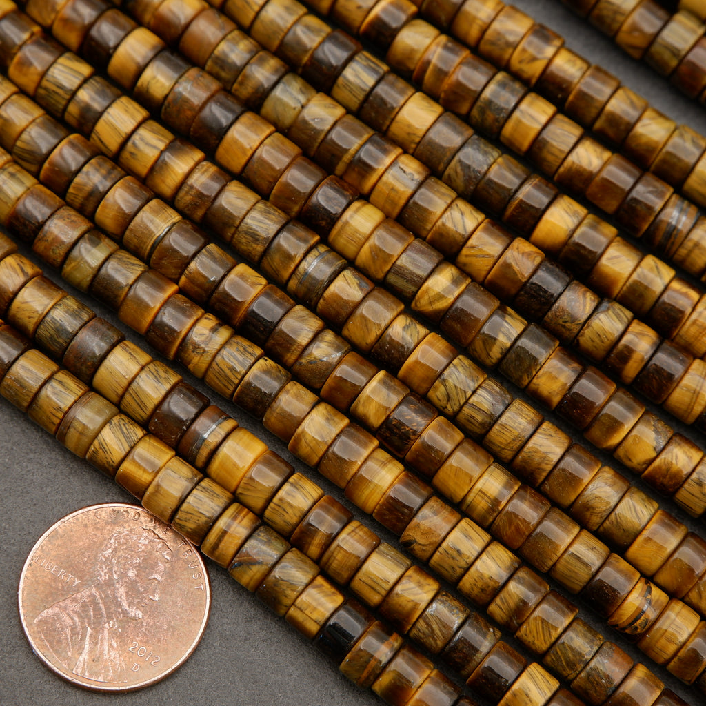 Polished tiger’s eye heishi beads in golden brown and bronze tones displayed beside a penny for scale.