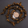 Necklace made of brown stone beads with a penny for scale on a dark background