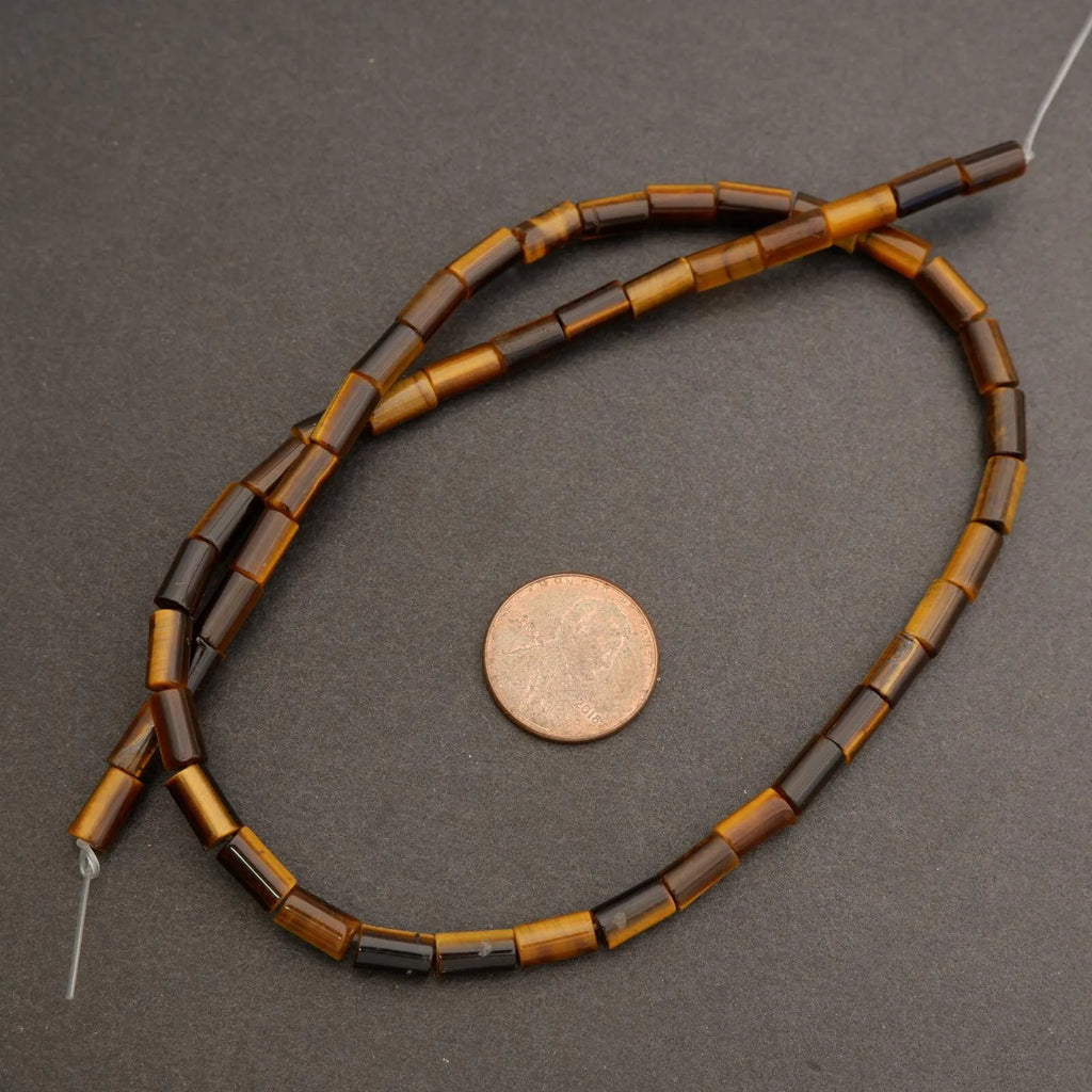 Beaded necklace with brown and black beads on a gray surface, next to a penny for scale.