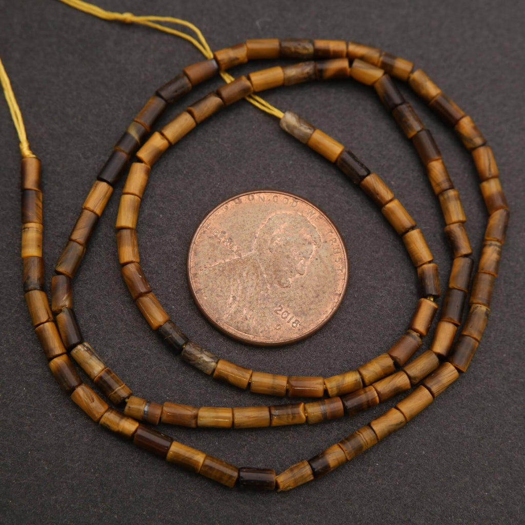 Beaded necklace with brown and yellow beads on a dark surface, next to a coin for scale.