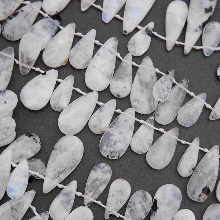 Teardrop-shaped white beads on a dark background