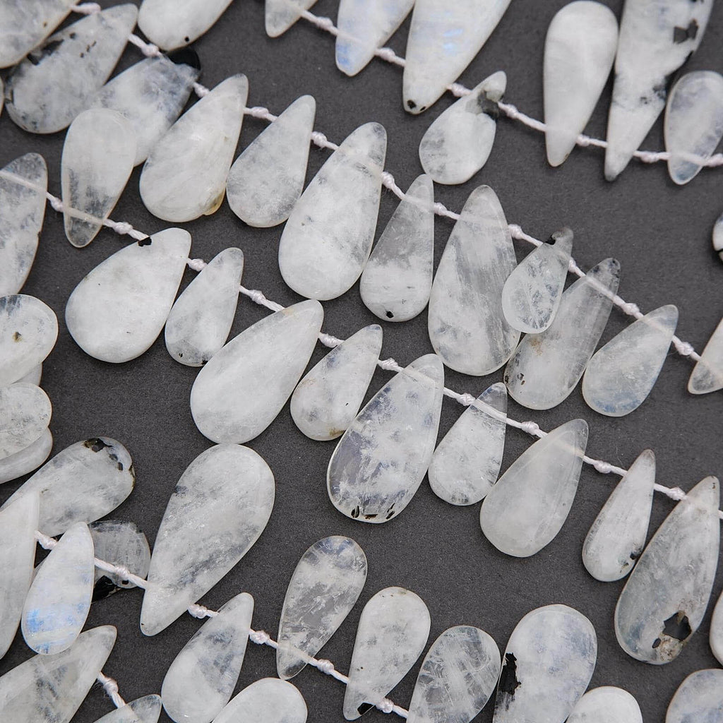 Teardrop-shaped white beads on a dark background