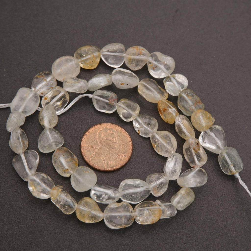 String of clear and yellow teardrop-shaped beads with a penny for scale on a dark surface