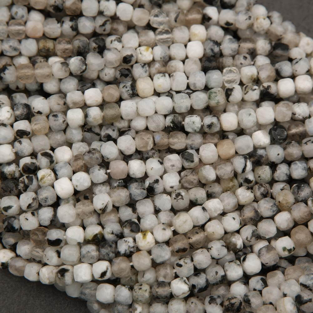Close-up of a string of small, round beads with a mix of white, beige, and black colors.