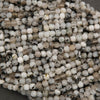 Close-up of a string of small, round beads with a mix of white, beige, and black colors.