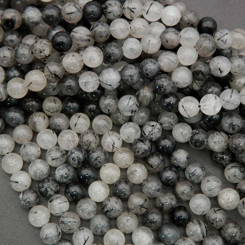 Polished tourmalated quartz beads featuring black inclusions in clear quartz