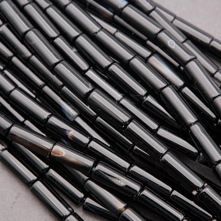 Close-up of black cylindrical beads on a gray surface