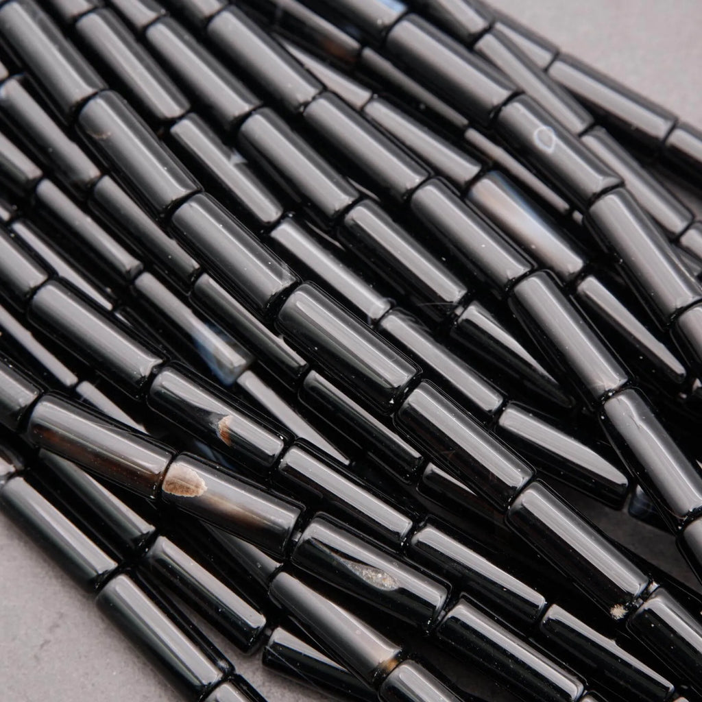 Close-up of black cylindrical beads on a gray surface