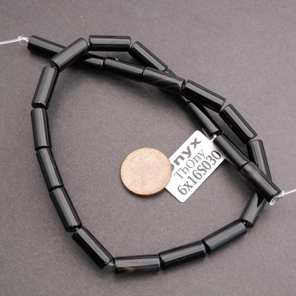 Black beaded necklace with a coin and label on a gray background