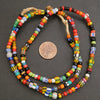Colorful beaded necklace with a penny for scale on a dark surface.