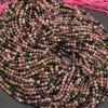 Multicolored bead string on a dark surface with pink thread in the background