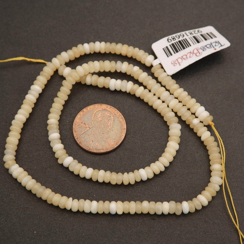 String of beads with a penny for scale on a dark surface, featuring a brand tag.