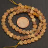 String of heart-shaped beads with a penny for scale on a dark surface