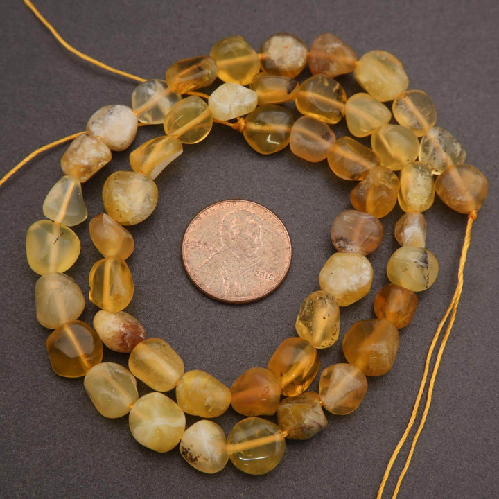 String of yellow beads with a penny for size comparison on a dark surface