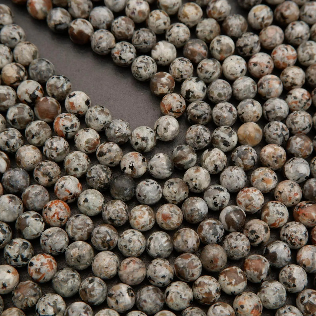 Close-up of round beads with a speckled pattern on a dark surface