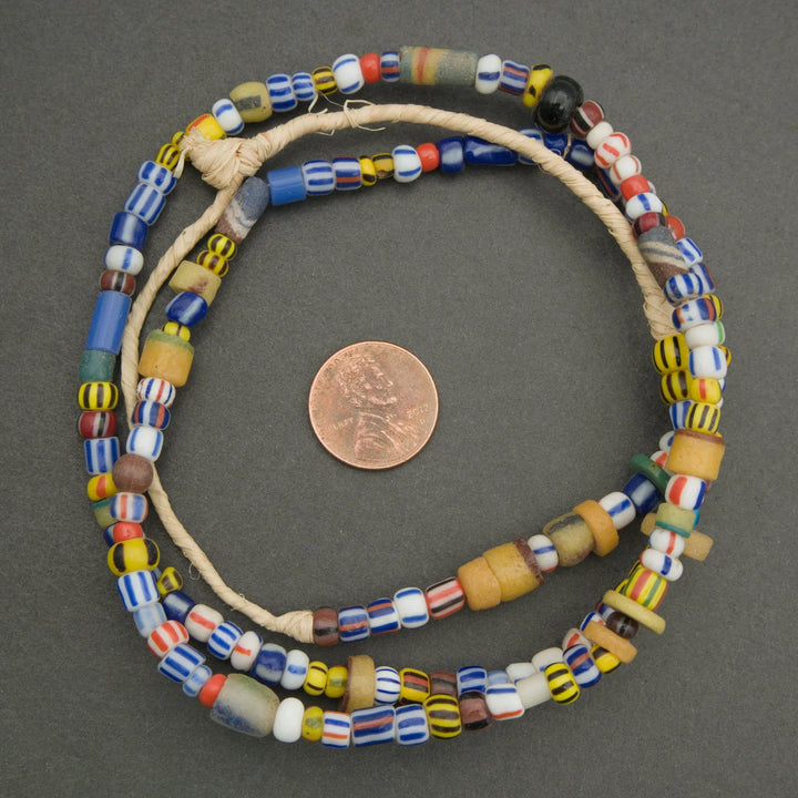 Colorful beaded necklace on a gray background with a penny for scale