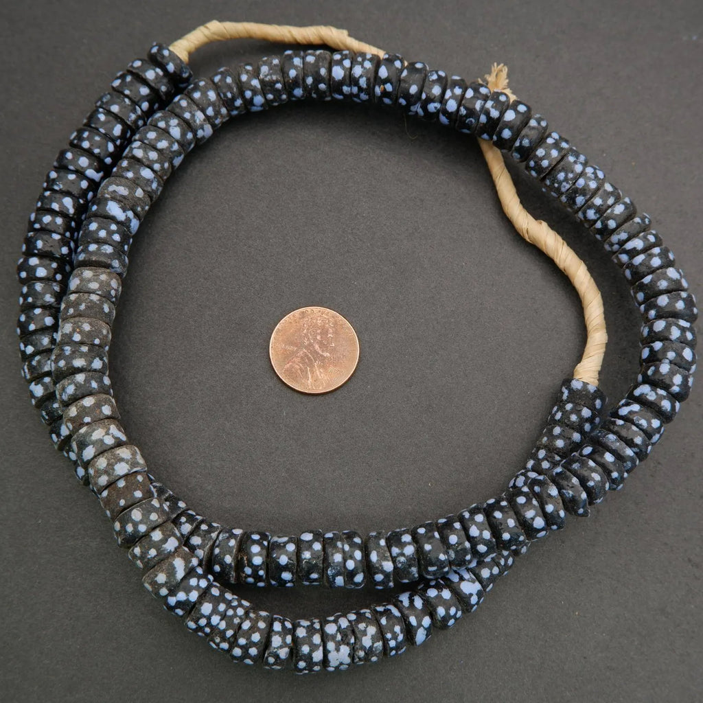 Black and white beaded necklace with a penny for scale on a gray background