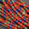 Close-up of colorful beads in red, blue, green, and orange on a gray background