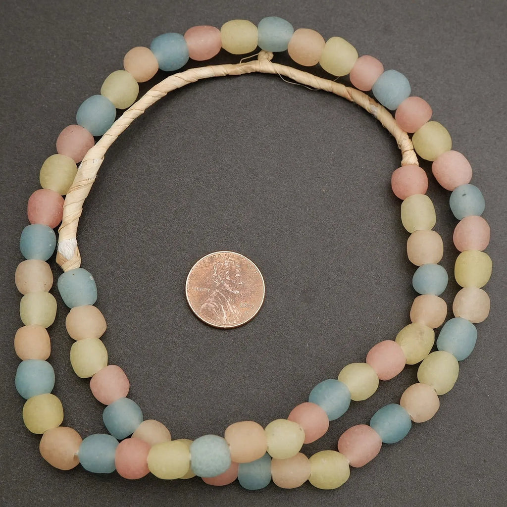 Necklace with pastel-colored beads on a dark gray background, next to a penny for size reference.